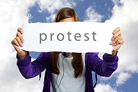 Junge Frau hält Schild mit Protest in der Hand