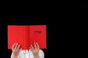 Rotes „Gesetzbuch“ mit kleiner Aufschrift TTIP vor schwarzem Hintergrund