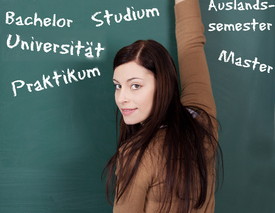 Studentin steht an Tafel, auf der verschiedene Begriffe rund ums Studium stehen.