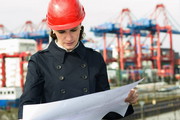 Bauingenieurin schaut auf Bauzeichnung, im Hintergrund Hafen (Kräne)
