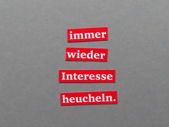 Ausgeschnitte Worte (weiß auf rot) auf grauem Hintergrund: „immer wieder Interesse heucheln.“