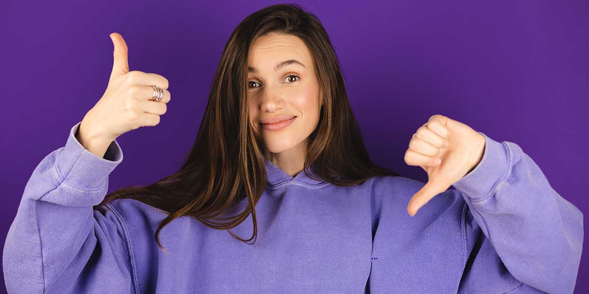 zvkate - stock.adobe.com Junge Frau hebt einen Daumen nach oben und senkt einen Daumen nach unten