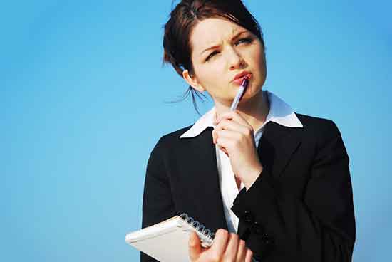 Eine junge Frau mit Stift und Block in der Hand überlegt