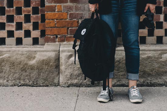 Person mit Rucksack vor Mauer