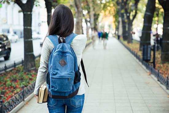 Studentin von hinten läuft einen Weg lang