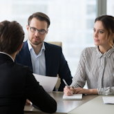 Bewerber im Gespräch mit HR-Verantwortlichen (je eine Frau und ein Mann)
