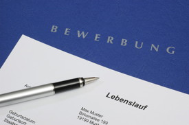 Auf der Bewerbungsmappe liegt der Lebenslauf mit einem Stift zur Seite