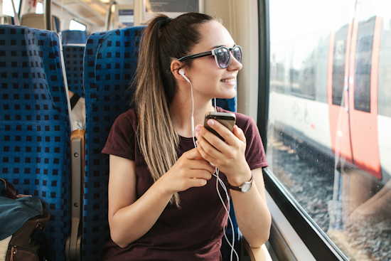 Studentin hört während einer Zugfahrt einen Podcast