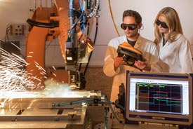 Student und Studentin mit Schutzbrille beim Fräsen