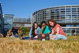 Studierende sitzen auf einer Wiese vor der HS Koblenz