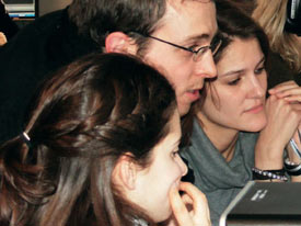 Drei Studierende schauen interessiert auf einen Computerbildschrim