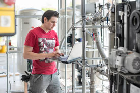 Student mit dem Laptop in einem Maschinenraum