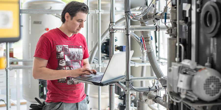 Student mit dem Laptop in einem Maschinenraum
