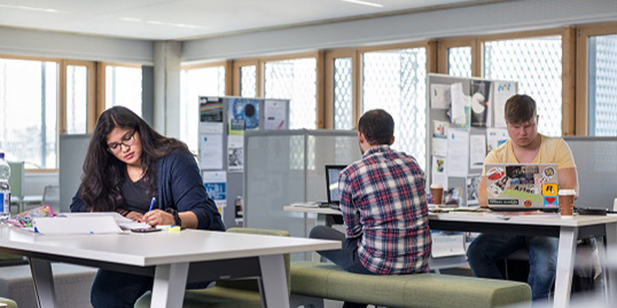 Studentin und Studenten arbeiten für sich an Tischen
