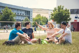 Studierende sitzen auf einer Wiese des Hochschulcampus