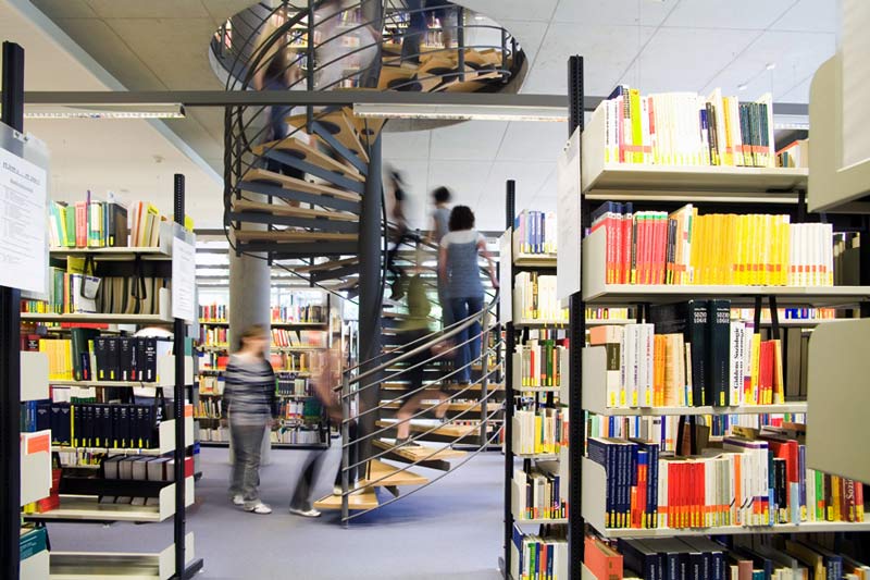Bibliothek, Studierende im Hintergrund auf der Wendeltreppe
