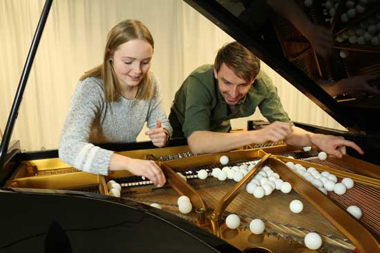 2 Studierende verteilen Tennisbälle im Inneren eines Flügels