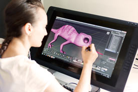 3-D-Modellierung in der Computergrafik: Studentin arbeitet an violettem Wesen auf dem Monitor