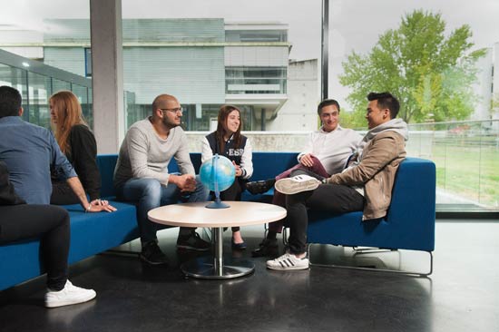 Studierende sitzen in einer Sitzgruppe vor einem Globus