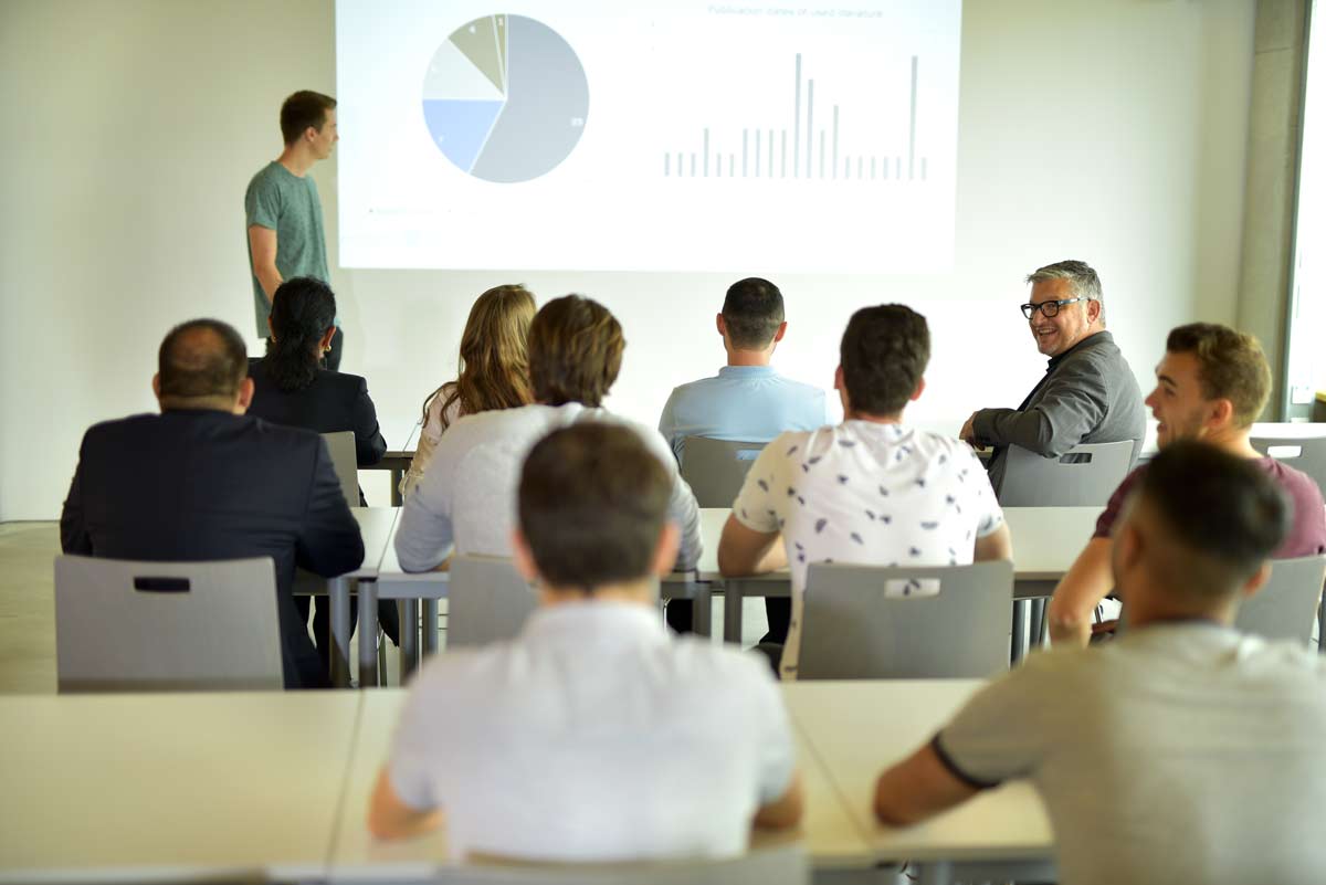 Studierende sind im Seminar und schauen einer Präsentation zu