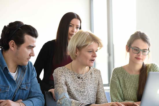 Professorin mit Studierenden am Rechner im Seminar