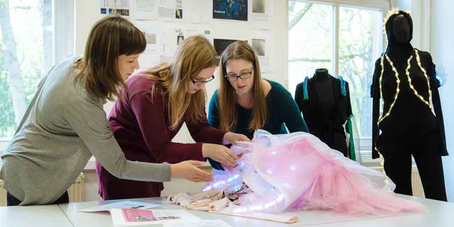 Studentinne bestücken ein Kleid mit digitalen Leucht-Elementen