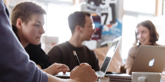 Studierende arbeiten gemeinsam an Laptops