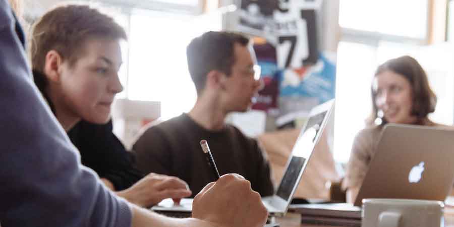 Studierende arbeiten gemeinsam an Laptops