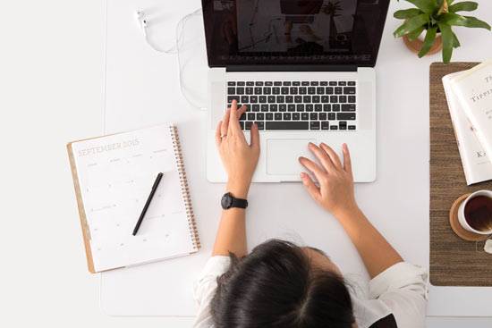 Person am Schreibtisch mit Laptop von oben