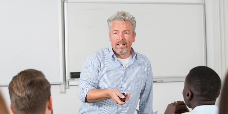 Dozent mit grauen Haaren und einer Fernbedienung