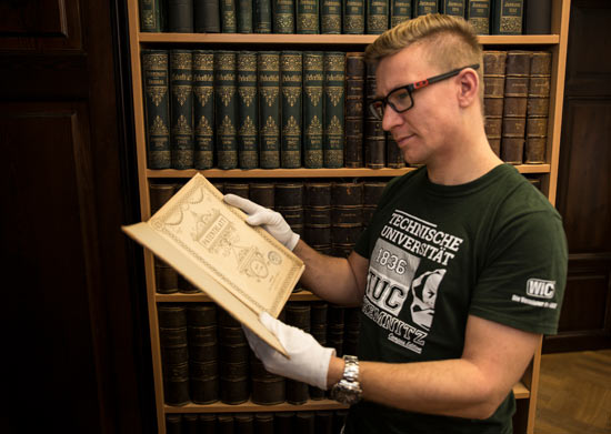 Student ist in der Bibliothek und hält ein Buch in der Hand