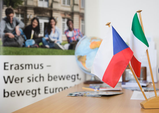 Schreibtisch mit Nationalflaggen, Erasmus-Plakat im Hintergrund