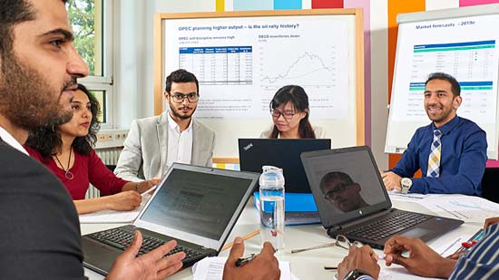 schick angezogene Studierende am Tisch, die etwas besprechen