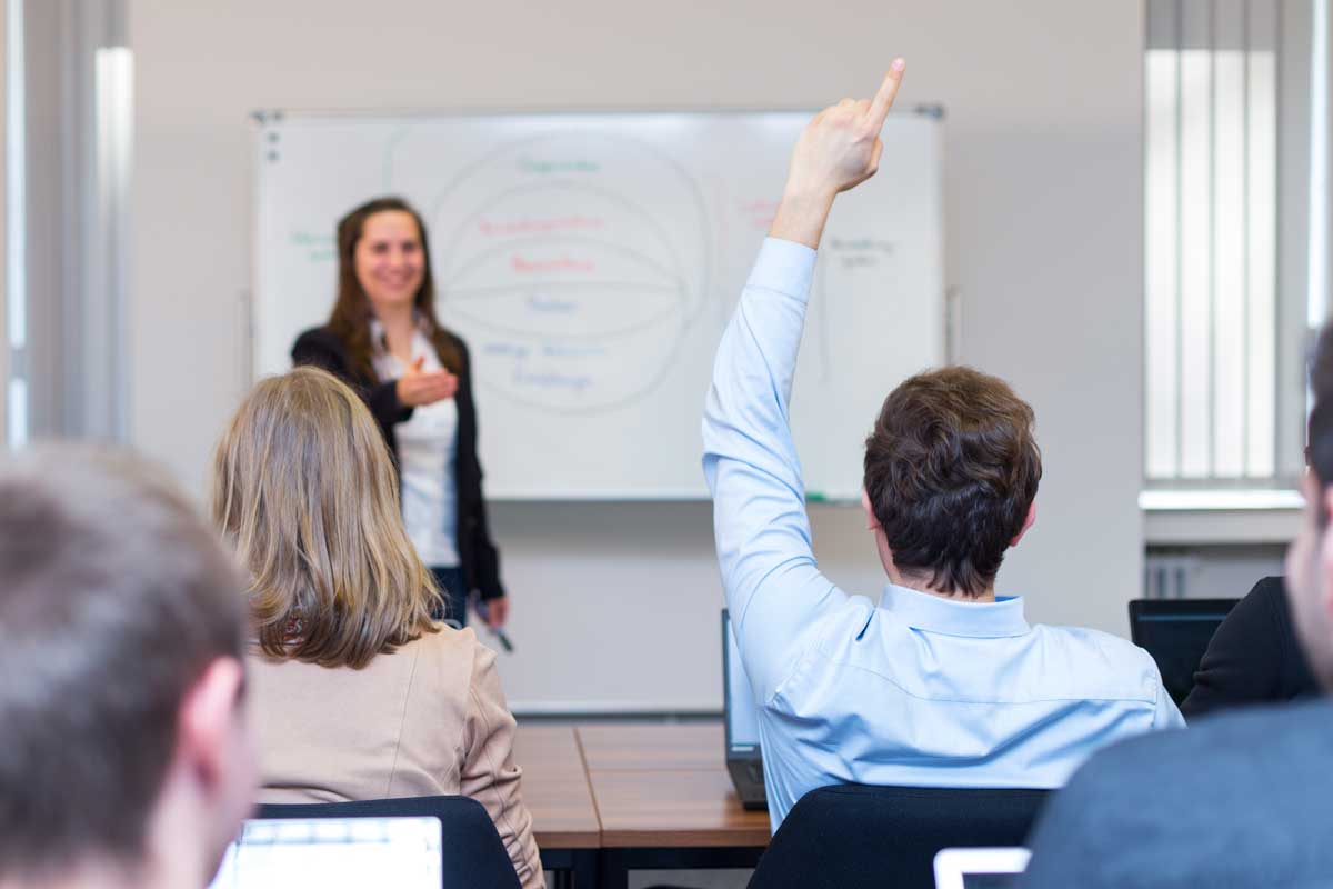 Ein Student meldet sich während eine Dozentin redet