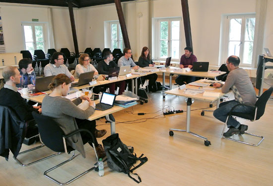 Studierende sitzen mit ihren Laptops an Tischen im Seminarraum