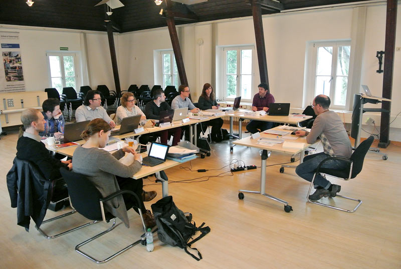 Studierende sitzen mit ihren Laptops an Tischen im Seminarraum