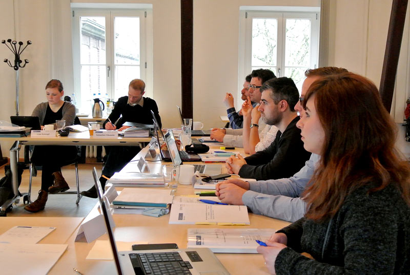 Studierende sitzen mit ihren Laptops an Tischen im Seminarraum