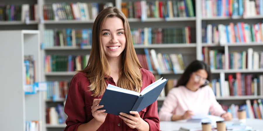 Eine Studentin liest ein Buch und grinst