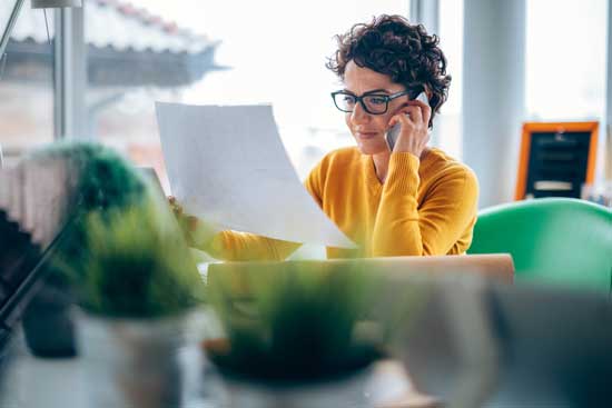 Frau am Telefon mit Papier