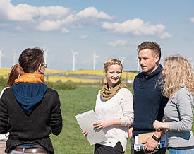 Studierende stehen draußen zusammen vor Windpark