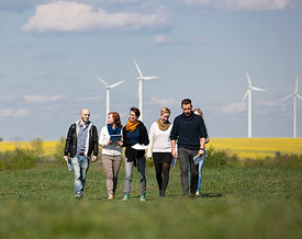 Studierende stehen draußen zusammen vor Windpark