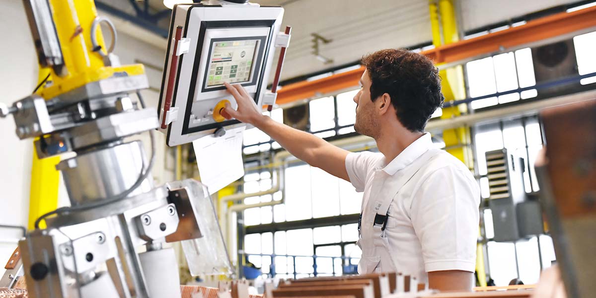 Mann an Steuereinheit einer Produktionsmaschine