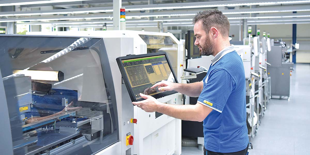 Mann an Steuereinheit einer Produktionsmaschine