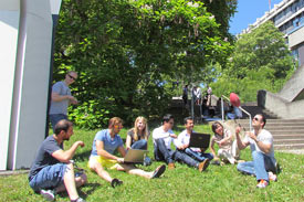 Studierende sitzen auf einer sonnigen Wiese