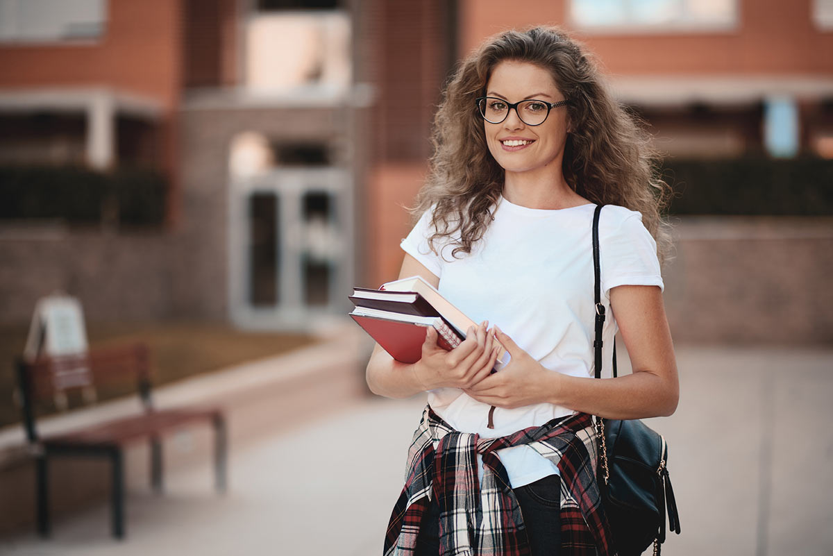 Studierende mit Büchern auf dem Campus
