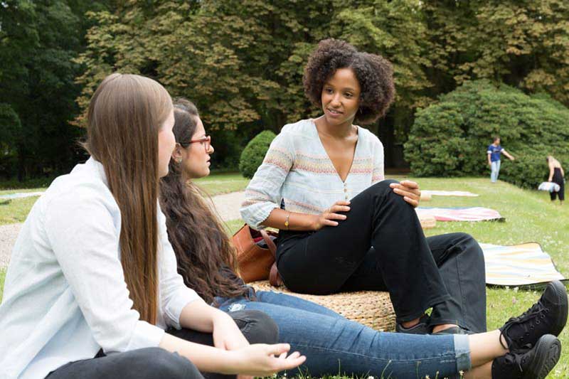 3 Studentinnen draußen auf Wiese