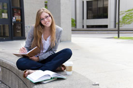 Studentin der HDBW vor Gebäude sitzend