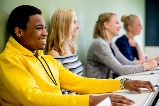 Studierende sitzen an Tischen