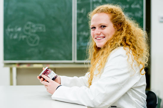 Studentin im Laborkittel mit Marmeladenglas