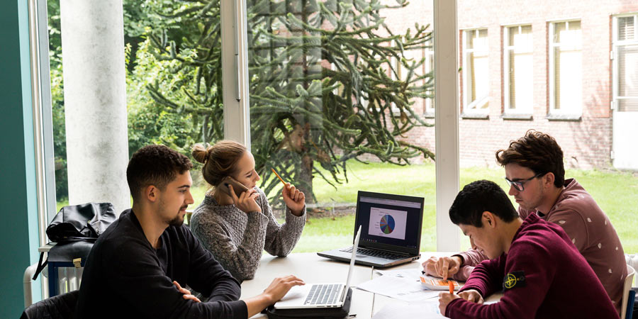 Studierende arbeiten zusammen am Tisch mit Laptop